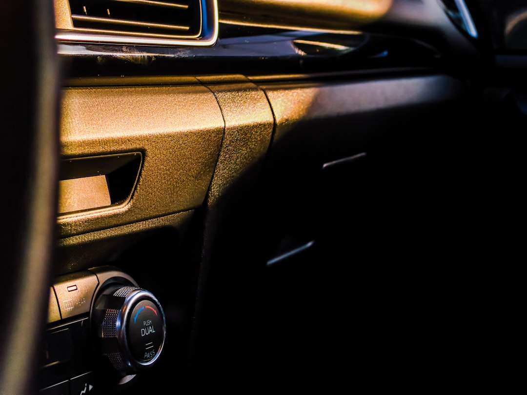 The interior of a car showing air vents and the glove compartment during sunset